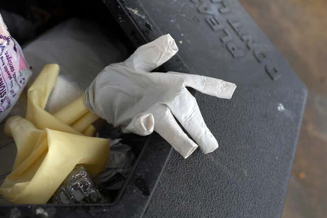 ALEXANDRIA, VA - MARCH 28: Two discarded rubber gloves sit in a trash can next to a gas pump.
