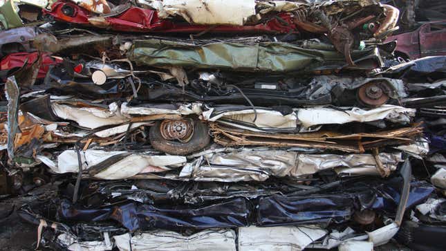 A photo of a pile of crushed cars at a scrap heap. 