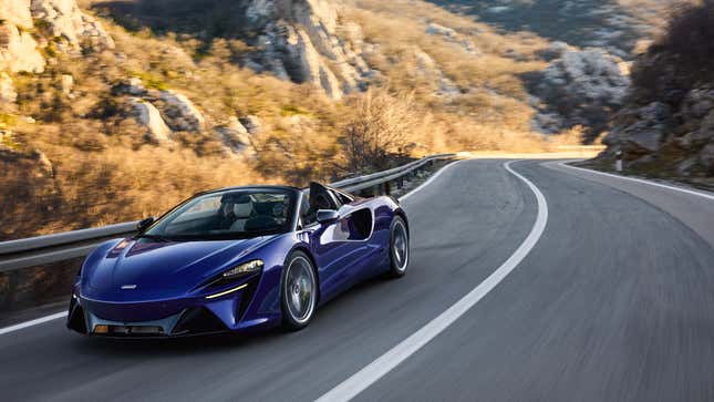 A photo of a convertible Mclaren sports car driving on a mountain road. 