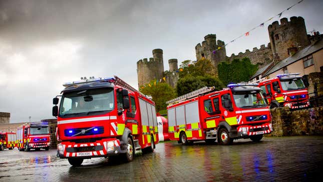 Four fire trucks parked outside a caste. 