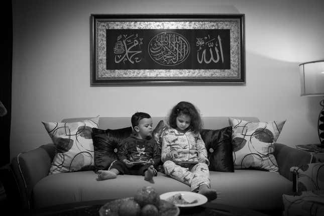 Souad and 2-year-old Hassan play on mobile devices as they sit together on the living room sofa.
