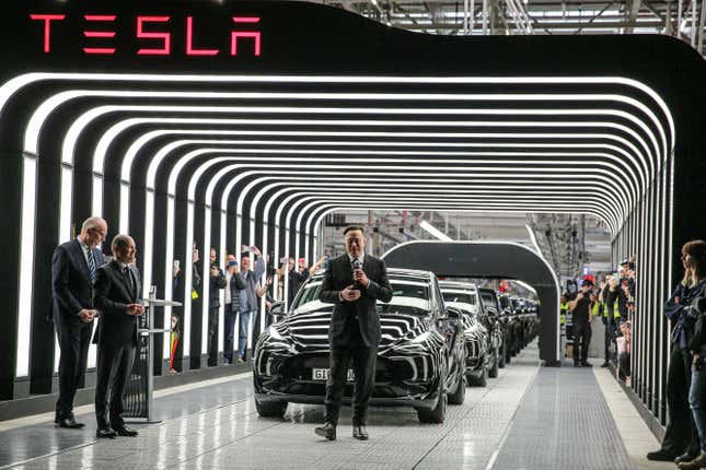 Elon Musk in front of a lineup of Teslas