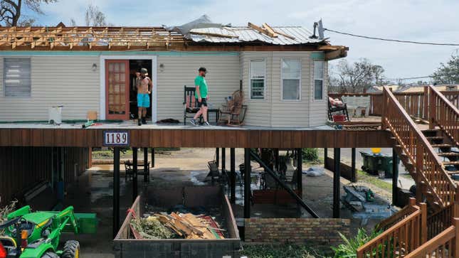 People walk across the deck of a home severely damaged by Hurricane Ida on Aug. 31, 2021 in Montegut, Louisiana.