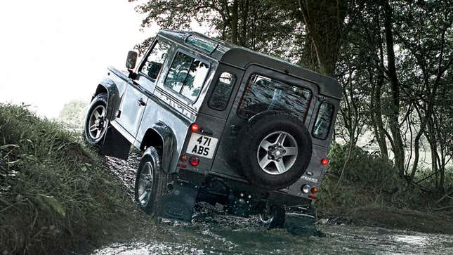 A Land Rover Defender drives out a river