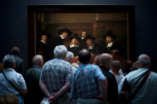 Museum visitors curiously viewing Rembrandt’s “Syndics of the Drapers’ Guild”