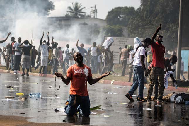 A supporter of Gabonese opposition leader Jean Ping prays in front of security forces.