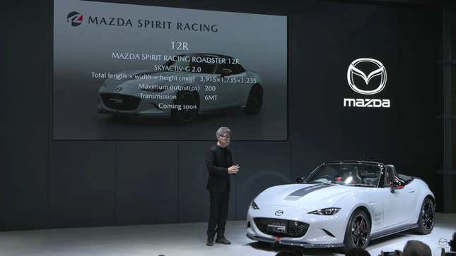 A photo from the press conference showing the MX-5 12R on a stage in front of a speaker and a slide about the car