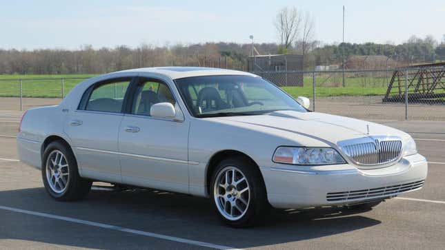 A front three quarters view of the white Lincoln Town Car in a parking lot