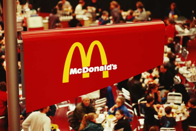 Des visiteurs assis sous un panneau McDonald’s à l’intérieur du Millennium Dome, conçu par Richard Rogers, à Greenwich.