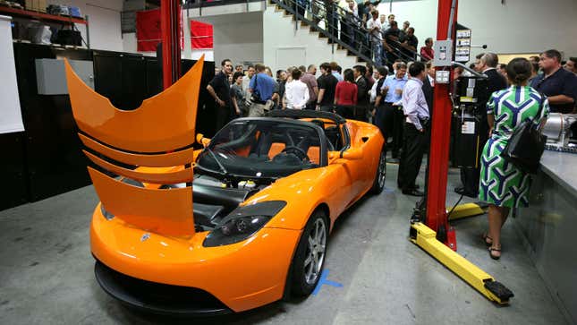 A photo of an orange Tesla Roadster on display in a crowd. 