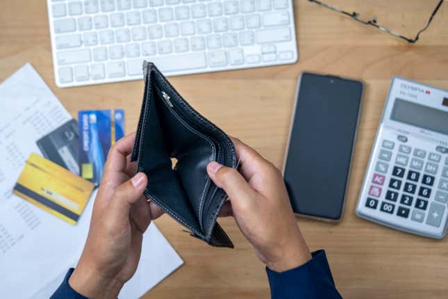 Close up man hand opening empty wallet over calculator.