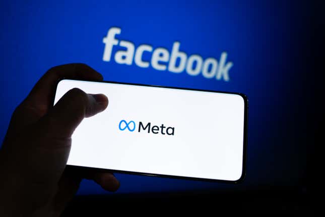 meta logo on a phone screen in front of a blue background with the word facebook