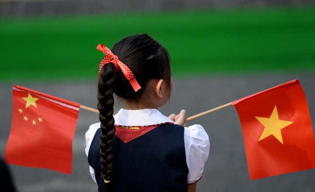 Um estudante vietnamita segura bandeiras vietnamitas e chinesas.