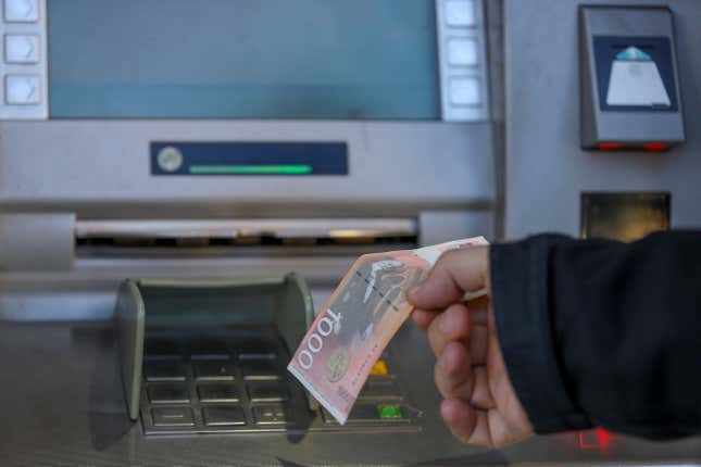 A man withdraws Serbian Dinars from a bank cash machine in northern Serb-dominated part of ethnically divided town of Mitrovica, Kosovo, Wednesday, Jan. 31, 2024. The ban on the Serbian currency was to start on Thursday. USA, Great Britain, France, Italy and Germany called Kosovo Prime Minister Albin Kurti to suspend enforcement of a regulation which bans the Serbian currency in Kosovo. (AP Photo/Bojan Slavkovic)