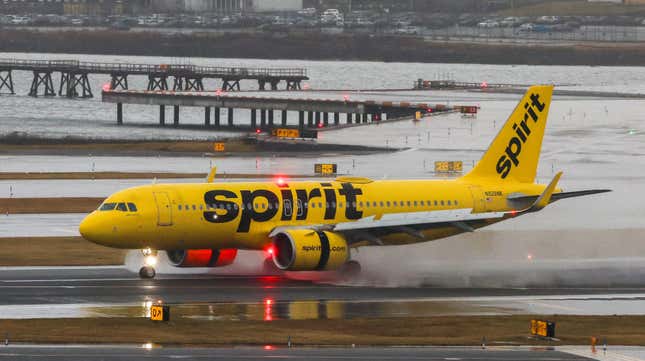 A Spirit Airlines plane lands on a stormy runway.