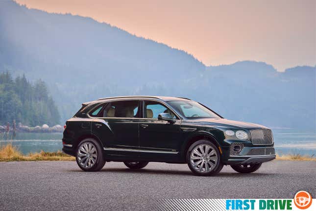 A green Bentley Bentayga SUV is parked in front of a lake.