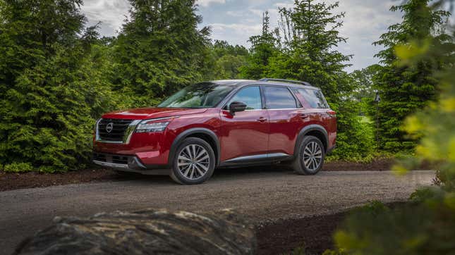 A red Nissan Pathfinder on an unpaved forest road