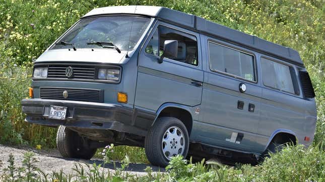 a blue 89 vanagon syncro driving up a grassy hill 