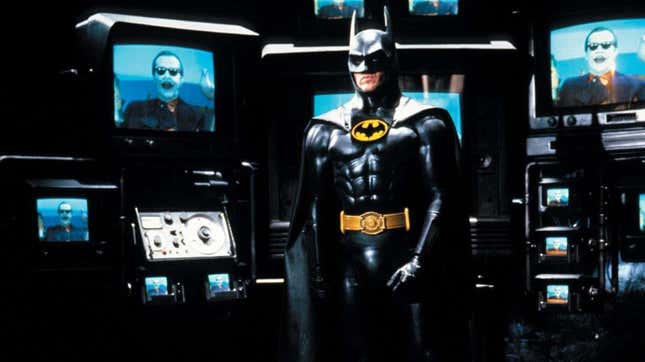 Michael Keaton's Batman stands surrounded by images of Jack Nicholson's Joker in the Bat Cave.