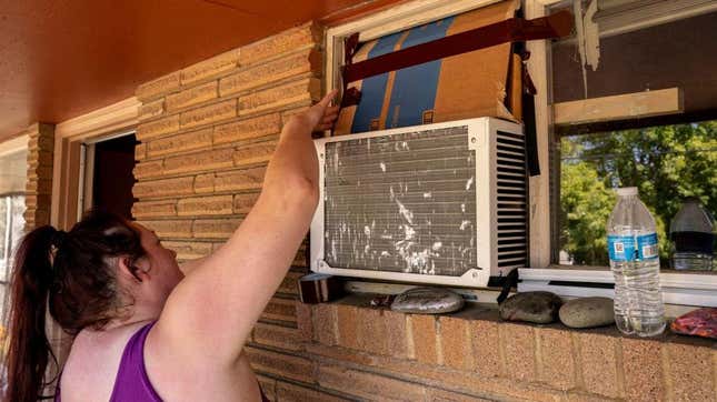 A Washington State resident arranges cardboard above an air conditioning unit during soaring temperatures on July 28, 2022. 