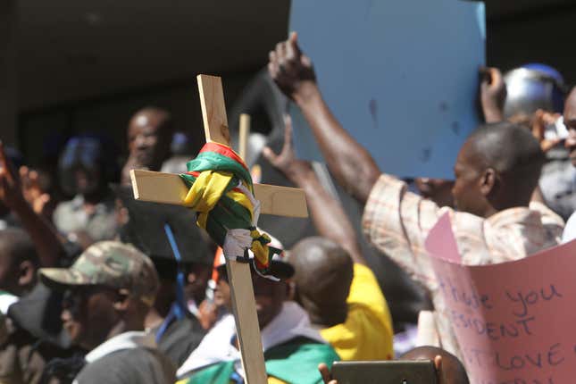 A cross with the Zimbabwean flag wrapped around it is lifted during demonstrations.