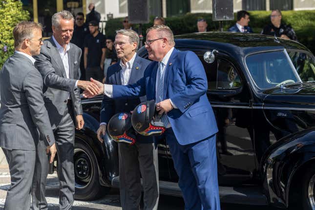 From left, Speedway Motorsports President and CEO Marcus Smith and NASCAR President Steve Phelps present Senate Majority Leader Paul Newton and House Speaker Tim Moore with vintage-style racing helmets during an announcement Thursday, Sept 28, 2023 outside the North Carolina Legislative Building in downtown Raleigh, N.C. The announcement was that the NASCAR All-Star Race will be held May 17-19 at the North Wilkesboro Speedway. (Travis Long/The News &amp; Observer via AP)