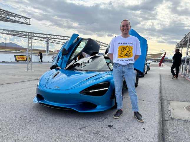 Front 3/4 view of a blue McLaren 750S Coupe with a human standing in front of it