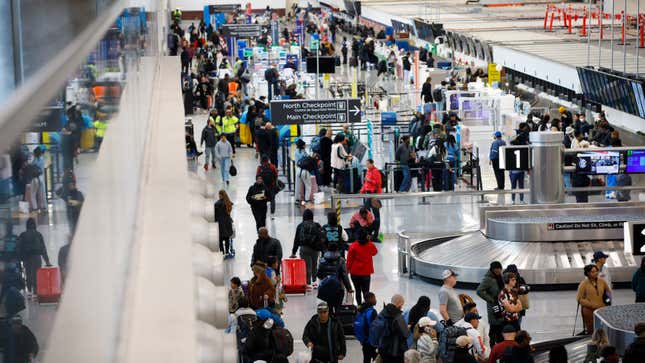 A photo of passengers queuing to collect bags at an airport. 