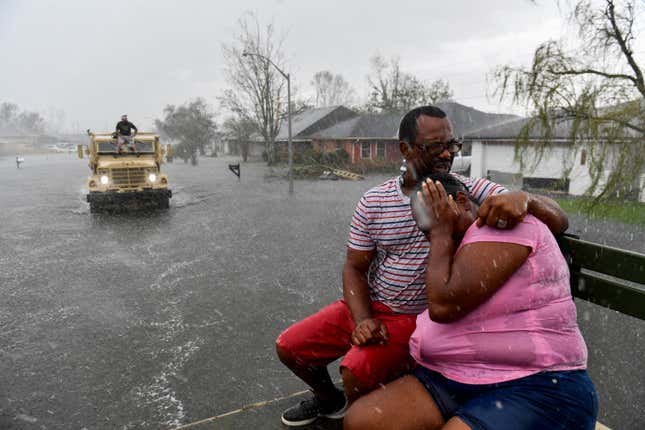 People react as a sudden rain shower soaks them with water while riding out of a flooded neighborhood in a volunteer high water truck assisting people evacuating from homes after neighborhoods flooded in LaPlace, Louisiana on August 30, 2021 in the aftermath of Hurricane Ida. - 