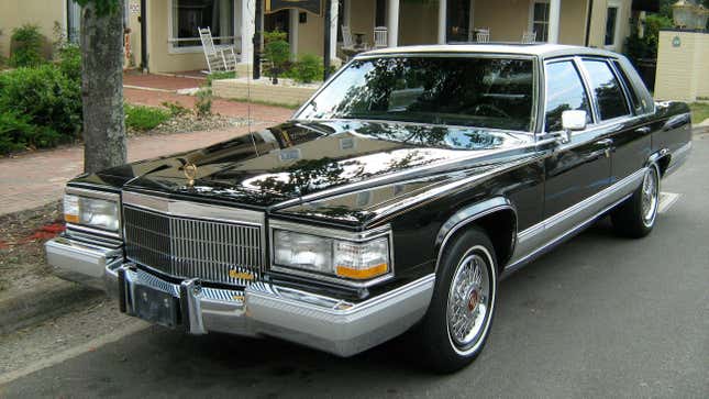 Un Cadillac Brougham negro impecable estacionado junto a tiendas