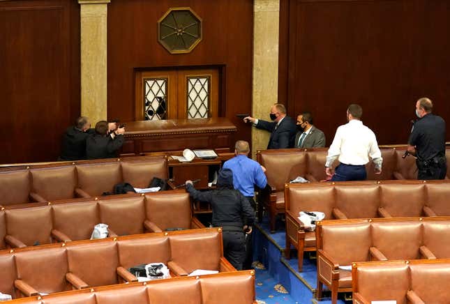 Capitol police officers point their guns at a door that was vandalized in the House Chamber during a joint session of Congress on January 06, 2021 in Washington, DC. Congress held a joint session today to ratify President-elect Joe Biden’s 306-232 Electoral College win over President Donald Trump. 