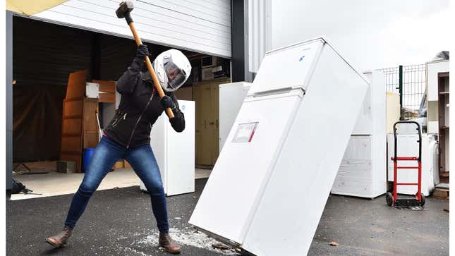 A photo of a woman smashing a fridge with a sledgehammer. 