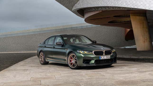 Une BMW M5 CS vert foncé garée devant un bâtiment chic