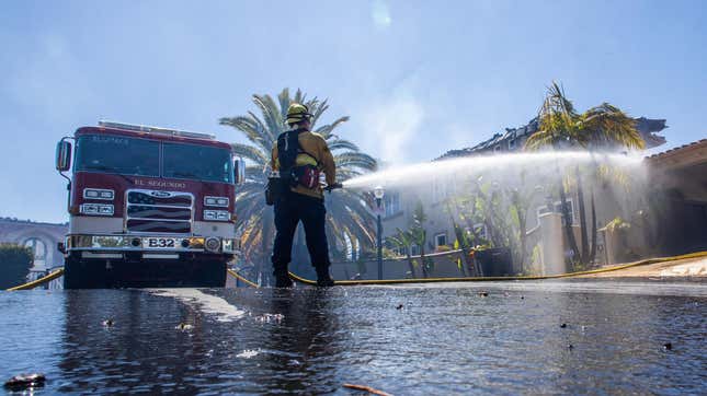 A firefighter uses a hose to fight hotspots at one of the homes destroyed by the Coastal Fire in Laguna Niguel, California, May 12, 2022.