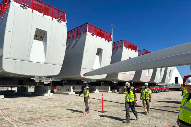 Workers walk by components of wind turbines being assembled at the State Pier in New London, Conn., on Wednesday, Oct. 4, 2023. The turbines will make up South Fork Wind Farm and eventually provide energy to New York. (AP Photo/Susan Haigh)