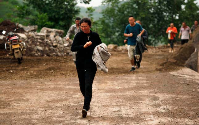 People run past a hillside alley which is at risk of landslide after an earthquake hit Ludian county of Zhaotong, Yunnan province August 3, 2014