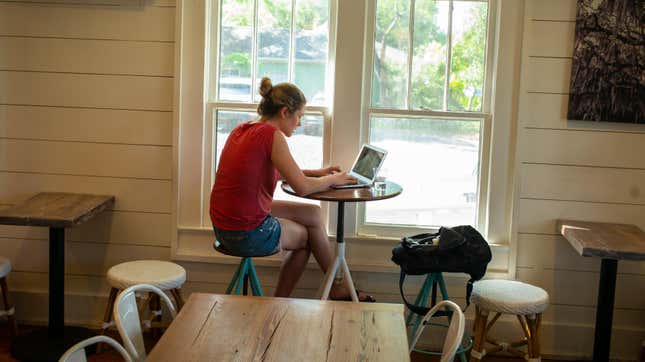 Eine Person, die in einem Café an einem Laptop arbeitet