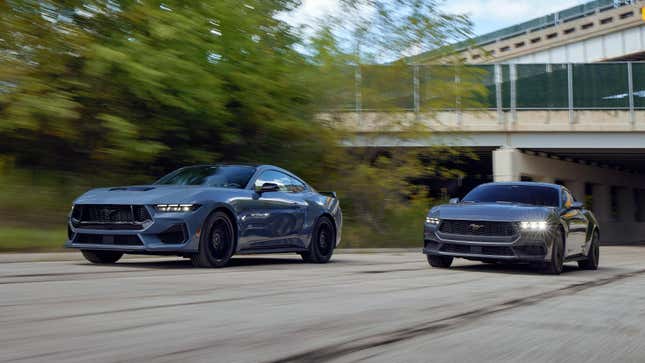 A pair of 2024 Ford Mustangs driving down a road side-by-side.