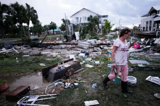 File - Jewell Baggett walks amidst debris strewn across the yard where her mother&#39;s home had stood, in Horseshoe Beach, Fla., after the passage of Hurricane Idalia, on Aug. 30, 2023. Information theft is on the rise. Frauds and scams often emerge during specific incidents such as the COVID pandemic, and in the wake of climate-related catastrophes. (AP Photo/Rebecca Blackwell, File)