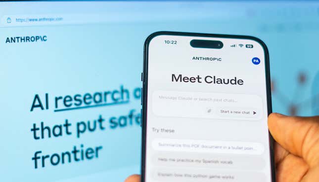 Claude 2 on a phone screen with Anthropic website displayed on a laptop in the background