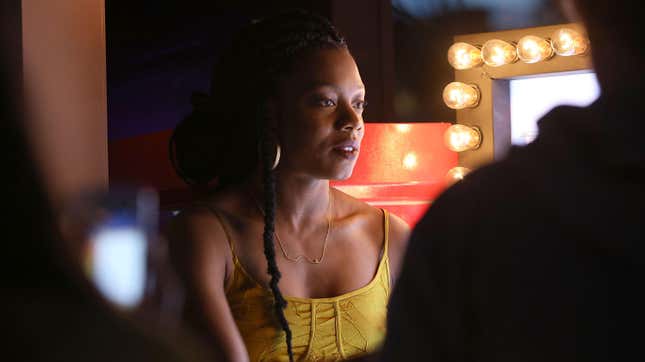 Nia DaCosta in a yellow outfit speaking to reporters at a press event.