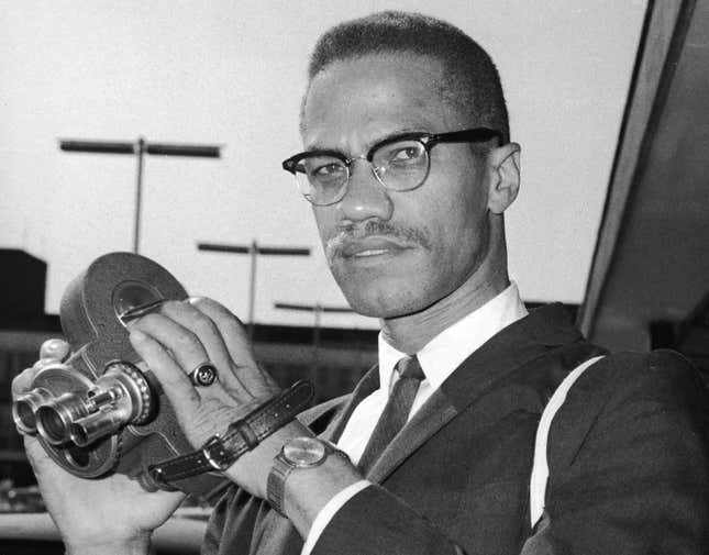 Malcolm X (1925 - 1965) as he holds an 8mm movie camera in London Airport, London, England, July 9, 1964.