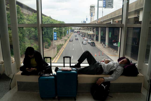 Carl Salazar (rechts) schläft am Ronald Regan Washington National Airport, während er am 19. Juli 2024 in Washington, DC auf einen verspäteten United-Flug wartet.