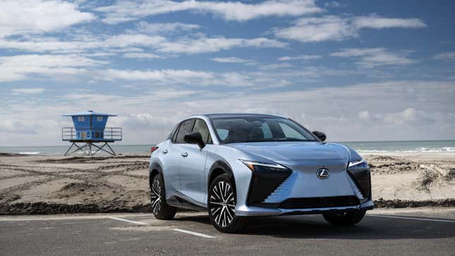 Un Lexus RZ azul claro estacionado frente a una torre de salvavidas en el estacionamiento de la playa