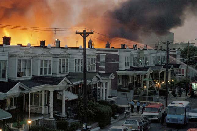 En mai 1985, des dizaines de maisons en rangée ont brûlé dans un incendie dans le quartier de West Philadelphia. La police a largué une bombe sur la maison du groupe militant MOVE, le 13 mai 1985, pour tenter d’arrêter ses membres, ce qui a conduit à l’incendie de dizaines de maisons dans le quartier.