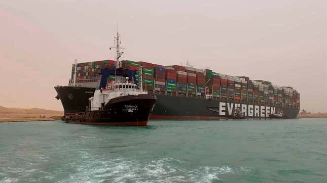 A boat navigates in front of the Ever Given, which turned sideways in Egypt’s Suez Canal, blocking traffic in a crucial East-West waterway for global shipping.