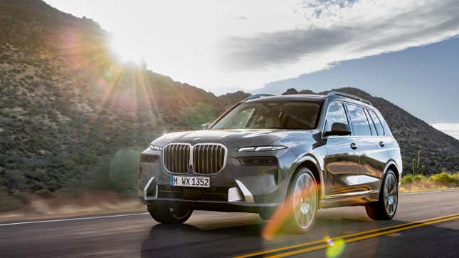 A gray X7 driving in front of a mountain at sunset