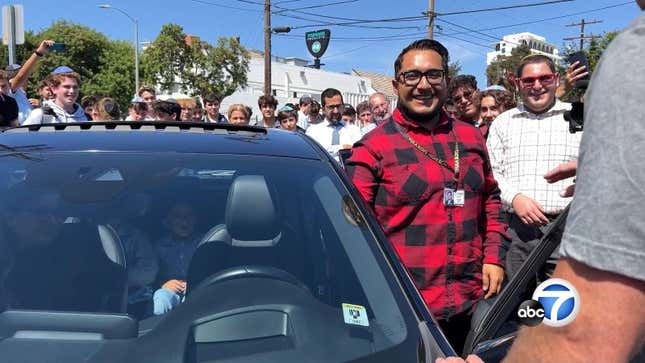 Teacher at Los Angeles private school poses with new car that students raised money to buy for him. 