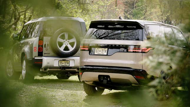 A photo of two Land Rover cars parked in a forrest. 