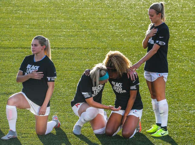 Julie Ertz prays with Casey Short. Rachel Hill is wearing blue nail polish.